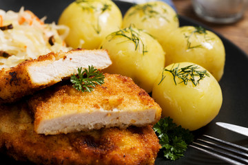 Fried pork chop in breadcrumbs, served with boiled potatoes and