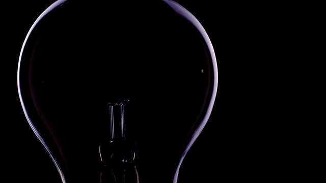 Loop of flashing electrical bulb on black background / switch on and switch of