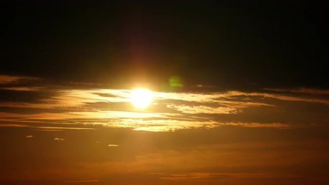 Mysterious telephoto time-lapse of clouds obscuring the orange sun. 4K UHD.
