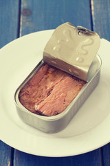 canned tuna on white plate on blue wooden background