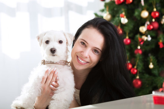 Smiling cute girl hugs her dog for christmas holiday