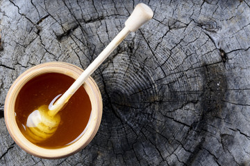 jar of honey and stick to honey on a wooden background