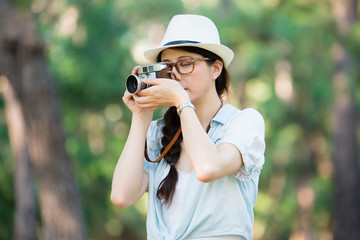 Beautiful young girl with retro camera photographing, outdoor