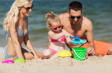 happy family playing with sand toys on beach