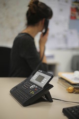 Frau im Büro greift zum Telefonhörer ist depressiv, traurig und telefoniert und braucht Hilfe