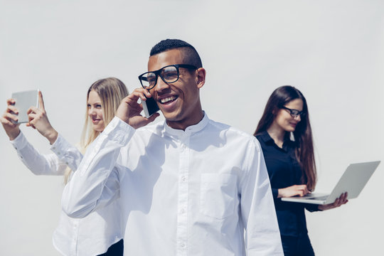 Three stylish young people with mini tablet, smartphone and laptop in front of white background