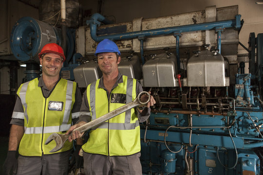 Portrait of two smiling mechanics in engine room on a ship