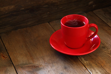 red cup of tea on wooden old table. retro filtered image
