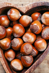 Fresh hazelnuts in a wooden bowl in the shape of a heart, top vi