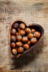Fresh hazelnuts in a wooden bowl in the shape of a heart, top vi