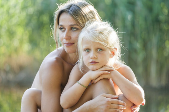 Mother and daughter cuddling at a lake