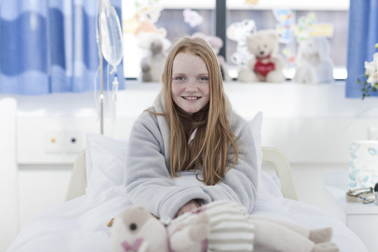 Portrait of smiling girl with red hair in hospital bed
