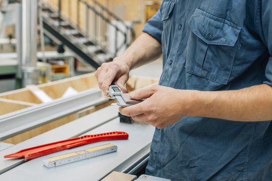Carpenter measuring piece of wood with caliper