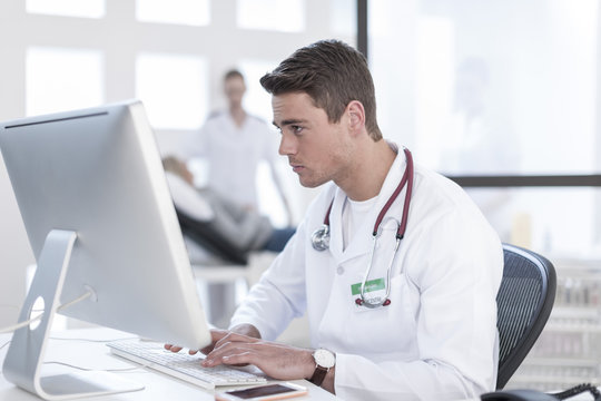 Doctor Sitting At Desk Working On Computer