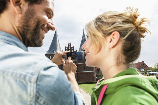Germany, Luebeck, couple taking picture in front of the Holsten Gate