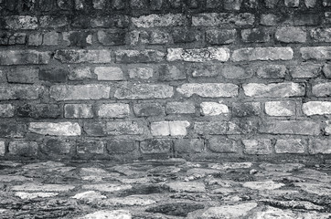 Old empty brick wall with stone floor.