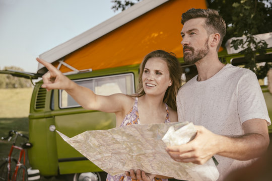 Couple with map in front of van in the nature