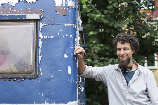 Smiling young man leaning on trailer