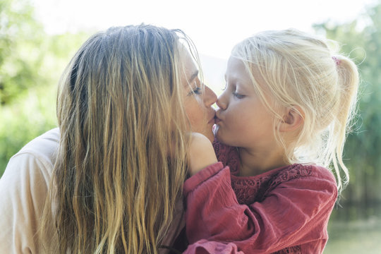 Mother and daughter kissing outdoors