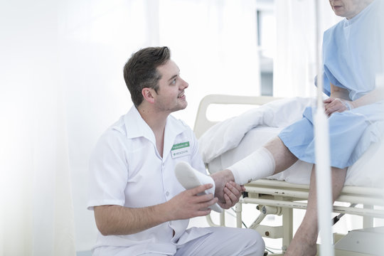 Nurse caring for senior patient in hospital bed
