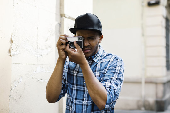 Young man with baseball cap and camera taking photos on the street