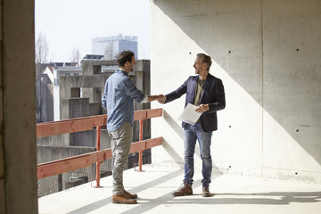Two men on construction site shaking hands