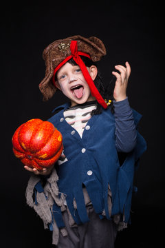 Adorable young boy dressed in a pirate outfit, playing trick or treat for Halloween. Studio portrait over black background