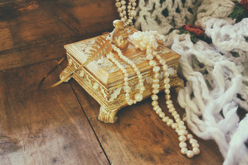 A beautiful antique golden jewelry box with natural white pearls on wooden table. retro filtered...