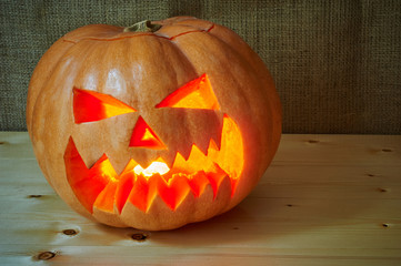 Halloween orange pumpkin jack lantern on a wooden background in