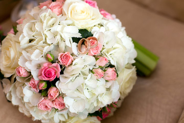 Two wedding rings at a bouquet of red and white roses