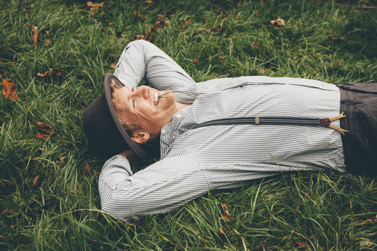 Smiling young man lying on a meadow with hands behind his head