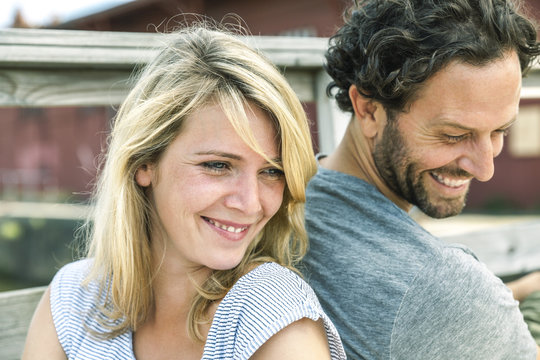 Smiling couple outdoors back to back