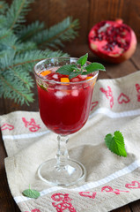 Pomegranate cocktail with orange zest, ice and mint on Christmas background