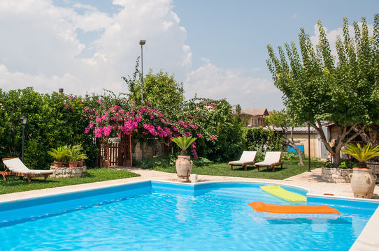 Swimming pool in a flower garden with mattresses
