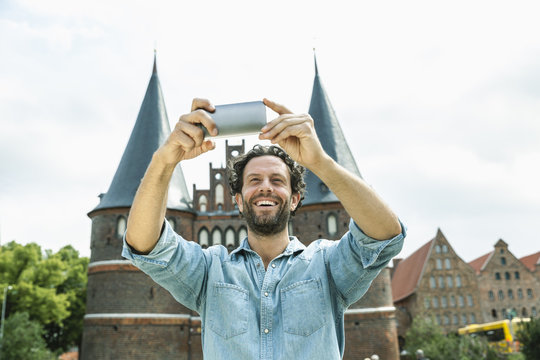 Germany, Luebeck, man taking selfie in front of the Holsten Gate