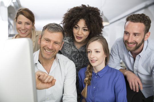 Smiling colleagues in office looking at monitor