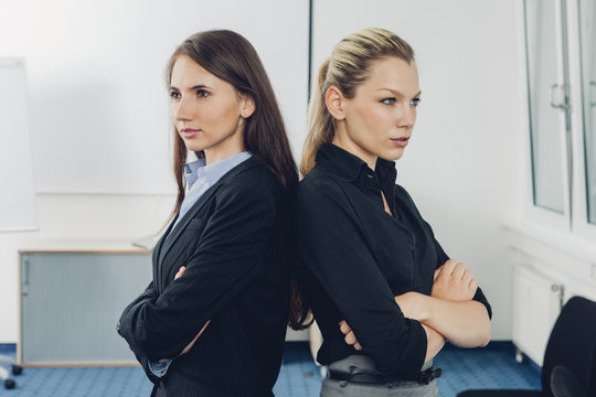 Two young businesswomen standing back to back