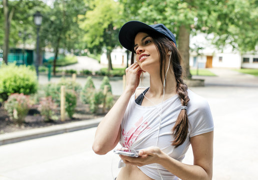 Portrait of young woman listening music with earphones in the park
