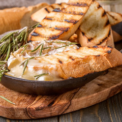 Homemade baked camembert with toasted bread and rosemary.