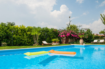 Swimming pool in a flower garden with mattresses
- 93219325