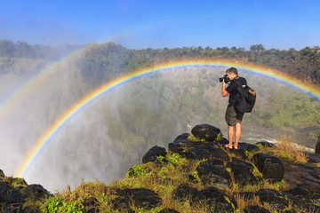Southern Africa, Zimbabwe, Victoria Falls, photographer with rainbow