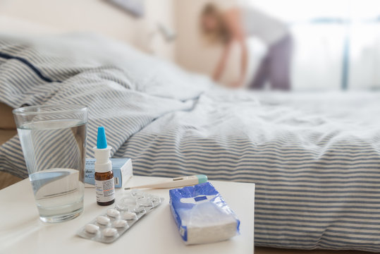 Junge Frau legt sich krank mit Erk&auml;ltung im Schlafzimmer hin