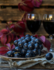 Black table grapes on plate with black wine