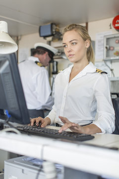 Female deck officer on bridge using computer