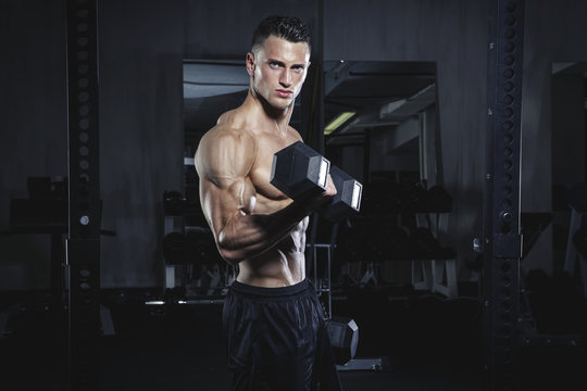 Physical athlete exercising with dumbbells