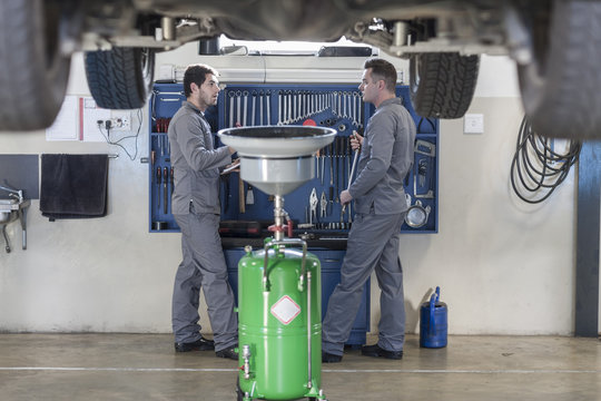 Two car mechanics at work in repair garage