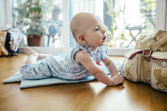 Portrait Of Baby Girl Lying On The Floor Lifting Head