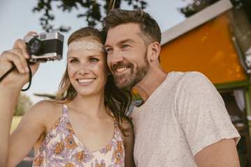 Happy couple taking a photo with analog camera
