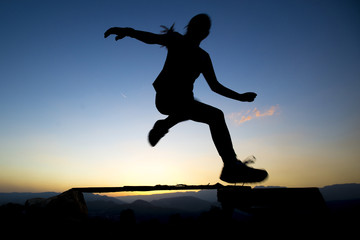Fototapeta premium jumping over obstacles at sunset young girl day