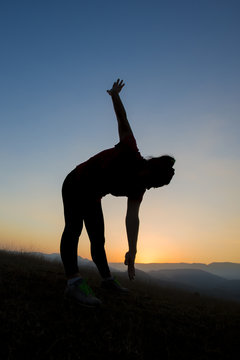 silhouette of young women who exercise at sunset